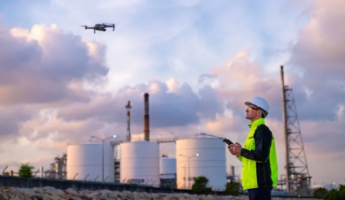 A drone pilot operates a remote control while monitoring a quadcopter drone