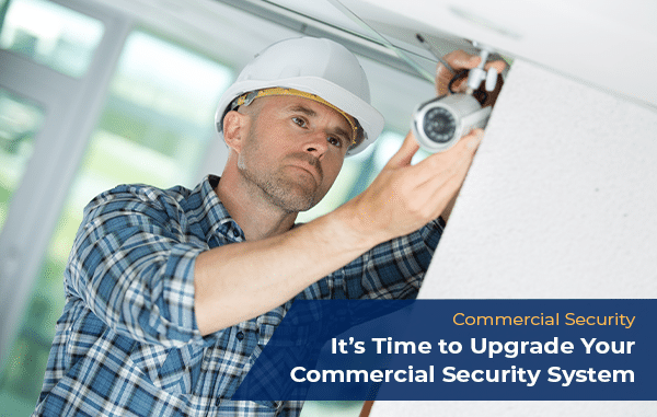 A professional technician installing a new security camera as part of a commercial security system upgrade.