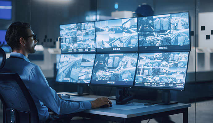 A security specialist in a control room monitoring multiple high-definition surveillance feeds