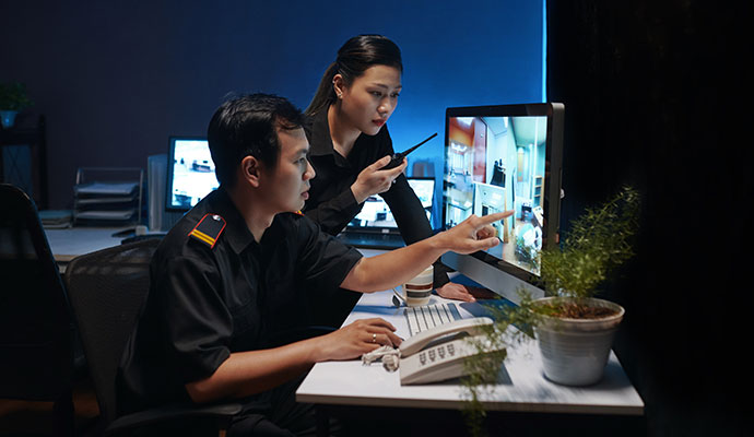 Two security professionals monitoring surveillance feed on a monitor