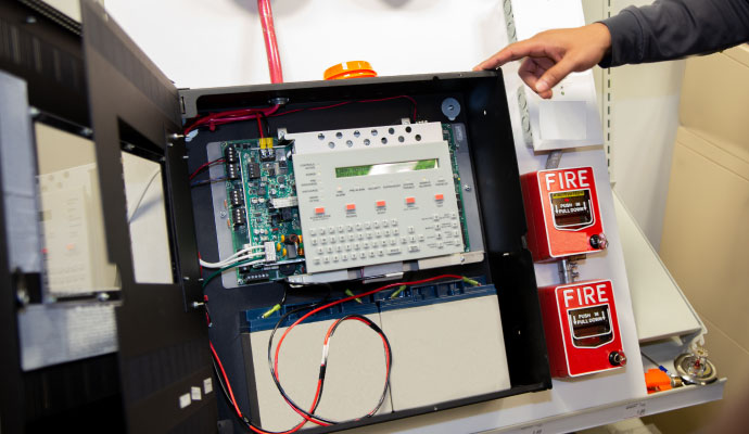 An open fire alarm control panel displaying a digital screen