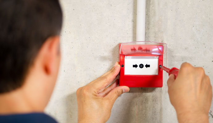 Technician installing a fire alarm pull station on a wall