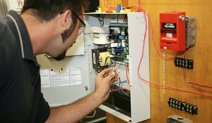 Technician repairing the wiring inside a commercial fire alarm control panel