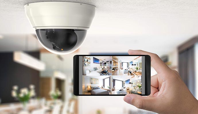 Smartphone displaying live home surveillance camera feeds beneath a ceiling security camera