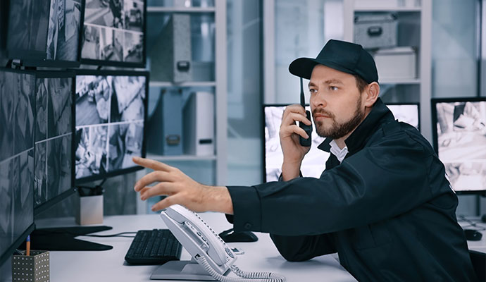 Security officer monitoring multiple surveillance screens in a control room