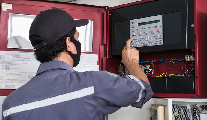 Technician inspecting fire alarm control cabinet