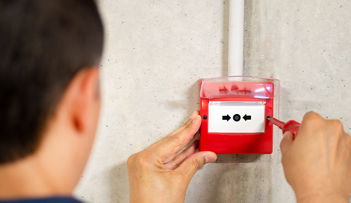 Technician installing fire alarm pull station