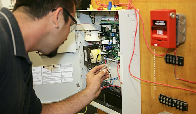 Technician servicing fire alarm control panel